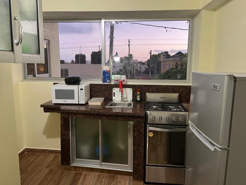 a kitchen with a stove and a microwave and a window at Hotel María Bonita Higüey, Apartments in Higuey