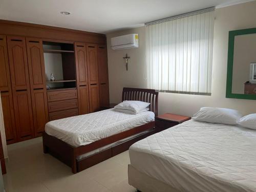 a bedroom with two beds and a cross on the wall at SUPER CASA CLUB CONDOMINIO EL PEÑON GIRARDOT in Girardot