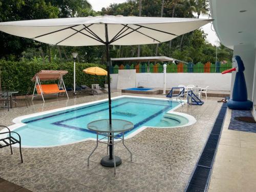 a swimming pool with a table and an umbrella at SUPER CASA CLUB CONDOMINIO EL PEÑON GIRARDOT in Girardot