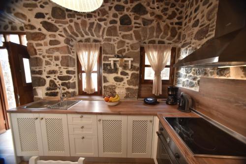 a kitchen with a stone wall and a counter top at Patriko Nisyrian Guesthouse in Mandrakion