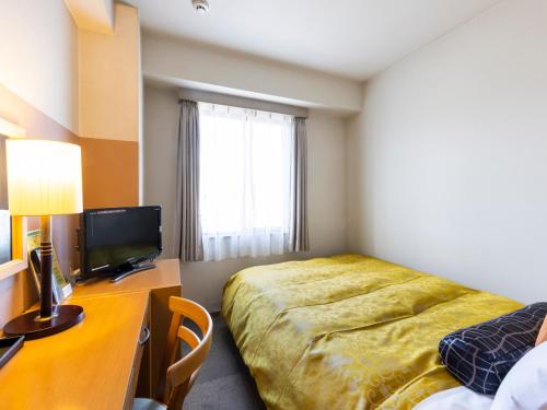 a hotel room with a bed and a desk with a television at Hotel Dorf Shizuoka in Shizuoka