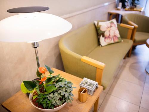 a table with a lamp and a chair and a couch at Hotel Dorf Shizuoka in Shizuoka