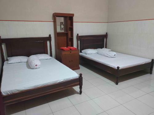 Habitación con 2 camas y espejo. en Penginapan Mentorogo Kaliurang Mitra RedDoorz en Kaliurang