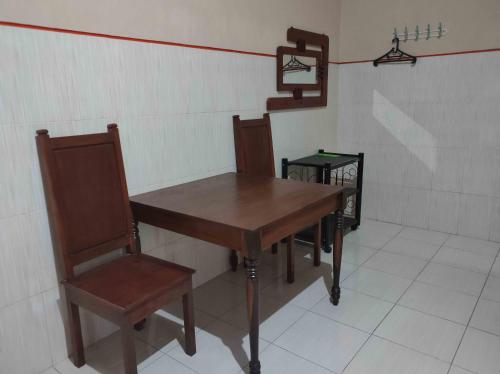 una mesa de madera y una silla en una habitación en Penginapan Mentorogo Kaliurang Mitra RedDoorz en Kaliurang