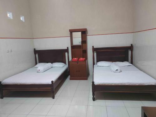 a room with two beds and a mirror and a cabinet at Penginapan Mentorogo Kaliurang Mitra RedDoorz in Kaliurang