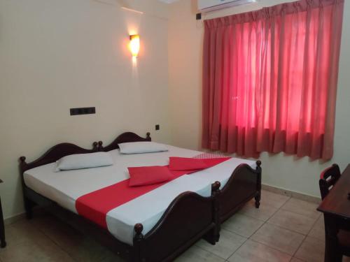 a bedroom with a large bed with red curtains at Eestee Rest in Colombo