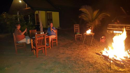 two people sitting around a fire pit at night at Ceylon Safari Cottage in Udawalawe