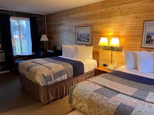 two beds in a hotel room with wooden walls at Riviera Motel in Mackinaw City