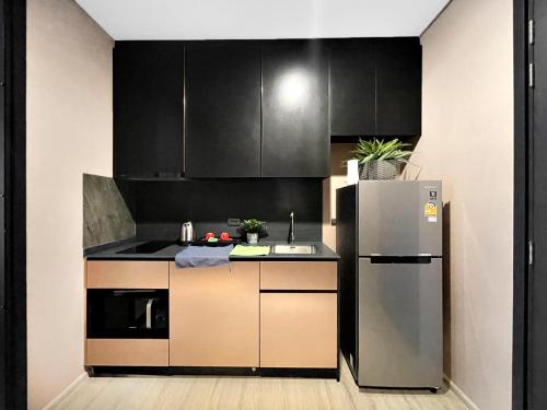 a kitchen with black cabinets and a stainless steel refrigerator at Edge Central Pattaya by J&P in Pattaya Central