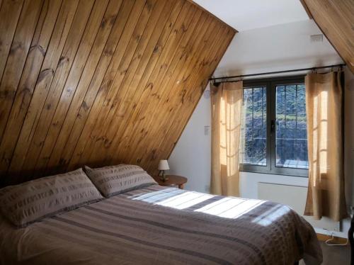 sypialnia z łóżkiem i drewnianą ścianą w obiekcie Casa El Ciprés w mieście Potrerillos