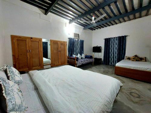um quarto com duas camas e uma televisão em Virasat E Punjab -Farmstay Amritsar em Nūruddīn