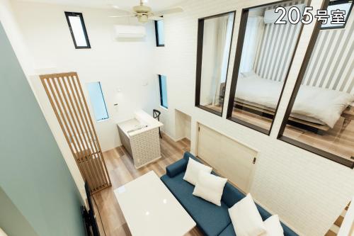 uma pequena sala de estar com um sofá azul e um espelho em YOUR ROOM 熊本駅 em Kumamoto