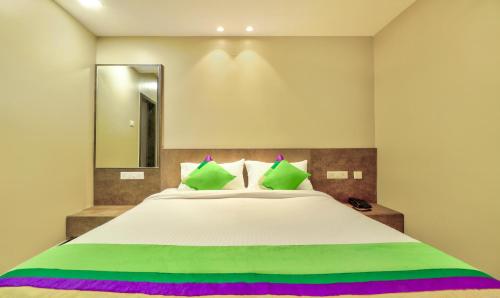 a bedroom with a large white bed with green pillows at Treebo Sriz Cozy Seethamadhara in Visakhapatnam