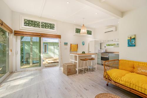 a living room with a yellow couch and a kitchen at The Other Place Cottage C in Folly Beach