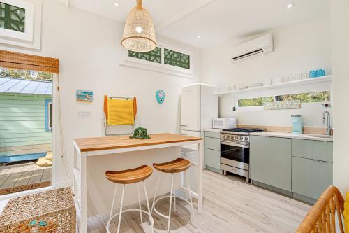 a kitchen with white walls and a counter with stools at The Other Place Cottage C in Folly Beach
