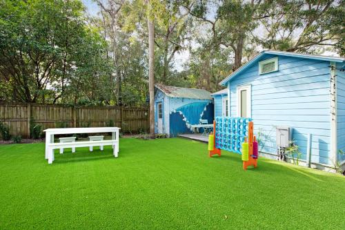 a yard with a bench and a blue house at The Other Place Cottage C in Folly Beach
