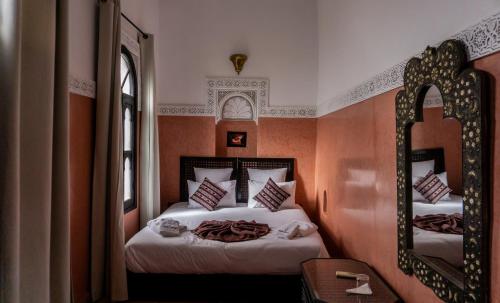 1 dormitorio con 2 camas y espejo en Riad Amegrad en Marrakech