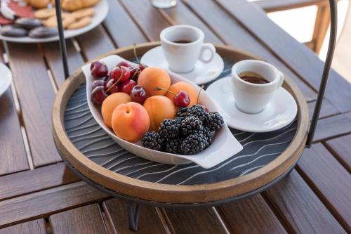 une assiette de fruits sur une table avec des tasses de café dans l'établissement Nidus 101, à Souda