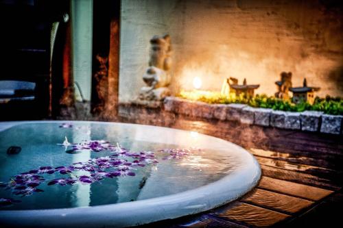 a bath tub filled with water with purple flowers in it at Hotel Balian Resort Tomei Kawasaki I.C. in Kawasaki