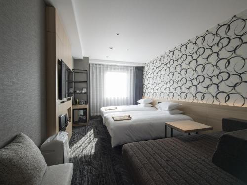 金沢市にあるTマークシティホテル金沢のベッド2台とソファが備わるホテルルームです。