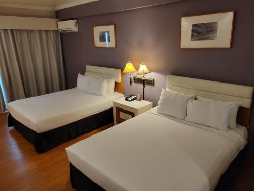 a hotel room with two beds and a lamp at Days Inn Guam - Tamuning in Tamuning