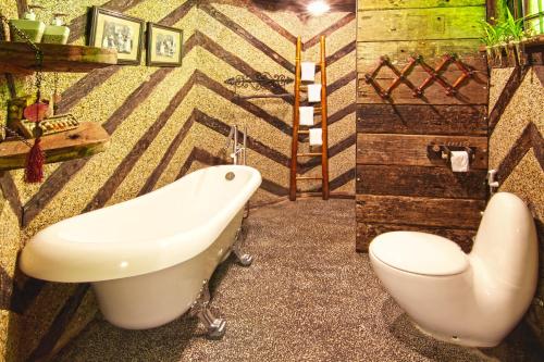 a bathroom with a bath tub and a toilet at Fig Tree Hills Resort (花果山度假村) in Bayan Lepas