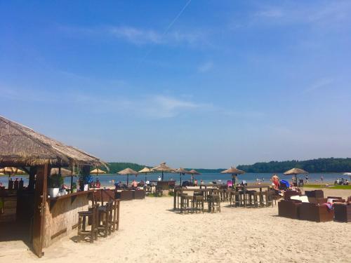 a beach with many tables and chairs and umbrellas at Ferienhaus am See in Templin