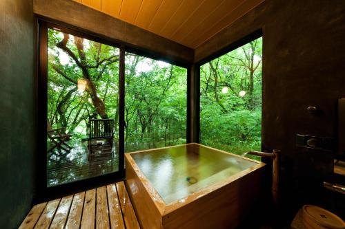 a bath tub in a room with a large window at Sen-no-Mori in Aso