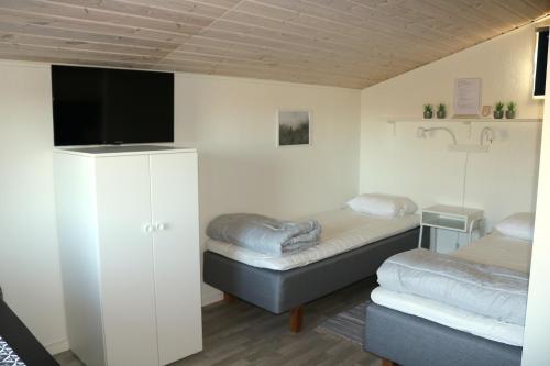 a room with two beds and a flat screen tv at Kärraton Stugor in Åhus
