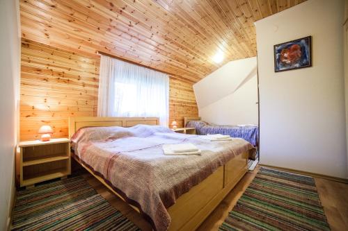 1 dormitorio con 1 cama y pared de madera en Pensiunea Szilas Panzió, en Păuleni