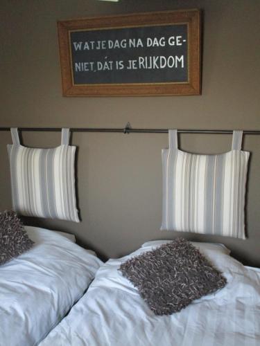 a bed with two pillows and a sign on the wall at B&B De Pethaan in Wielsbeke