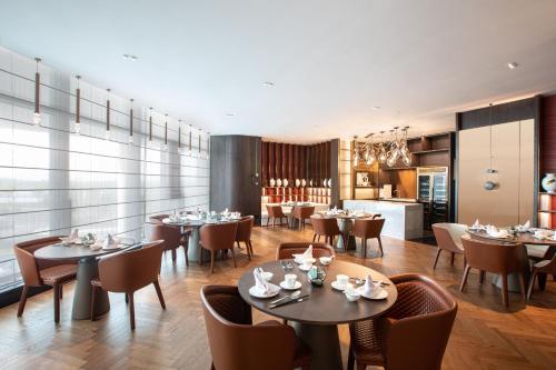 a restaurant with tables and chairs and a kitchen at Wyndham Garden Nanjing Airport in Nanjing