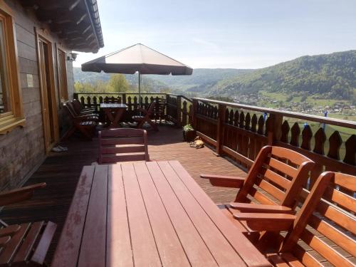 una terraza de madera con mesa, sillas y sombrilla en ORLIK - pokoje gościnne, en Uście Gorlickie