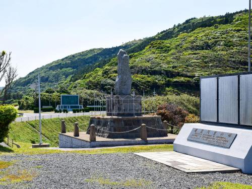 a statue in a park with a mountain in the background at Hanareya in Tsushima