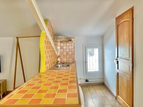 - une cuisine avec un sol en carrelage orange et jaune et un évier dans l'établissement Grand studio sur la Marine, à Sète