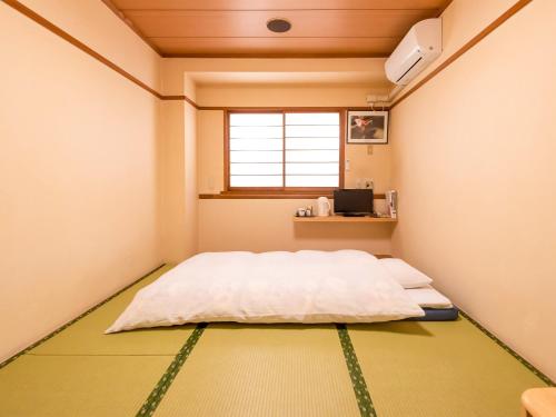 a bedroom with a bed in a room with a window at Sakura Ryokan Asakusa Iriya in Tokyo