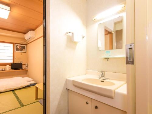 La salle de bains est pourvue d'un lavabo et d'un miroir. dans l'établissement Sakura Ryokan Asakusa Iriya, à Tokyo