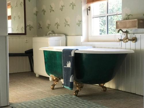 eine grüne Badewanne in einem Badezimmer mit Fenster in der Unterkunft Sea Breeze Cottage in Eisma