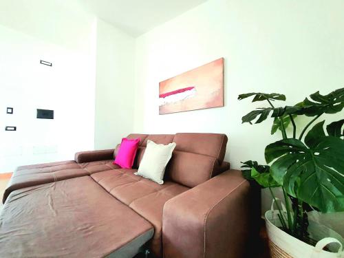 a brown couch in a living room with a plant at Villini Cortesas in Orosei