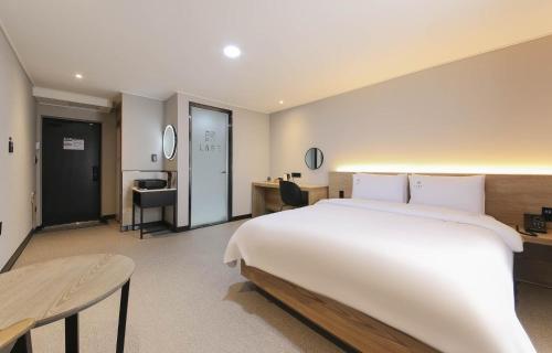 a bedroom with a large white bed and a desk at LABE Hotel in Jeonju