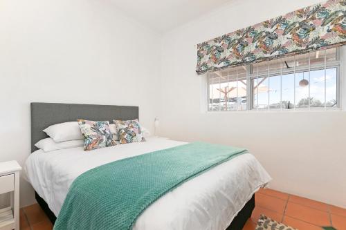 Un dormitorio con una cama con una manta verde y una ventana. en Kite Villa Langebaan, en Langebaan