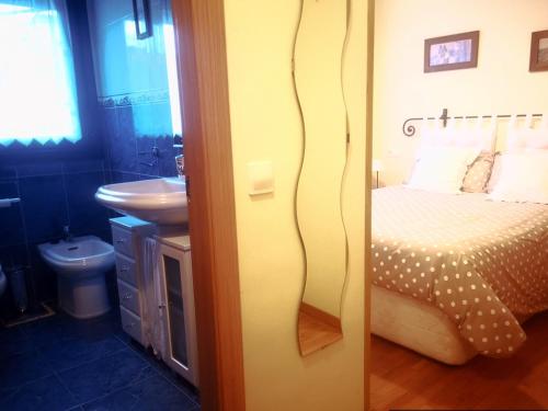 - Baño con dormitorio con cama y lavamanos en LA LUNA DE LUANCO, céntrico, confort y con parking, en Luanco