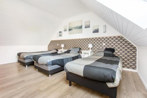 un dormitorio en el ático con 3 camas y una escalera en Maison Alice /Maison avec vue sur les champs, en Comines