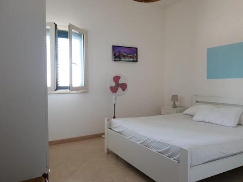 a white bedroom with a white bed and a window at Appartamenti La Spiaggia in Gallipoli