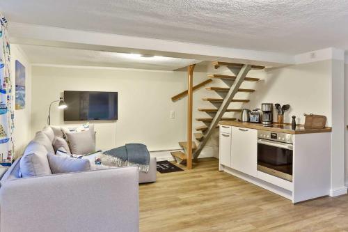 a living room with a couch and a kitchen with a spiral stairs at Naturidyll Mariendorf - Reethus Rotbuche in Mariendorf