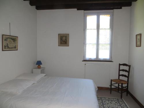 a bedroom with a large white bed and a chair at La Ferme de Montboulan in Salbris