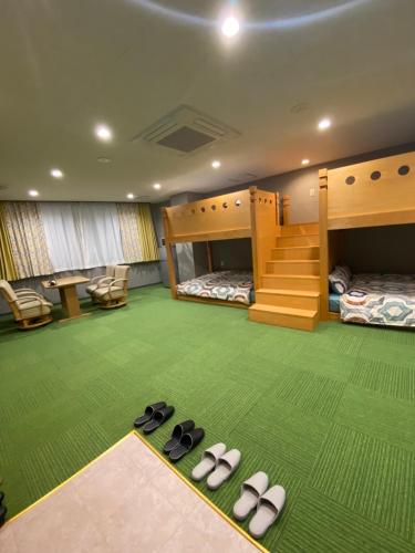 a room with two bunk beds and slippers on the floor at kdy ｽﾃｲﾊｳｽ 2段ベットの広い客室みんな一緒に泊まれる in Kumamoto