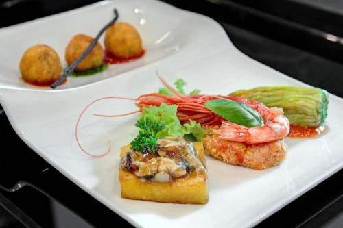 a white plate with shrimp and other foods on it at LHP Napoli Palace & SPA in Naples