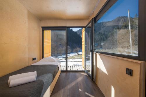 a room with two beds and a large window at ROOMBOX Likani in Borjomi