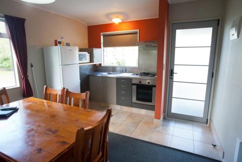 a kitchen with a wooden table and a refrigerator at Kennedy Park Resort Napier in Napier